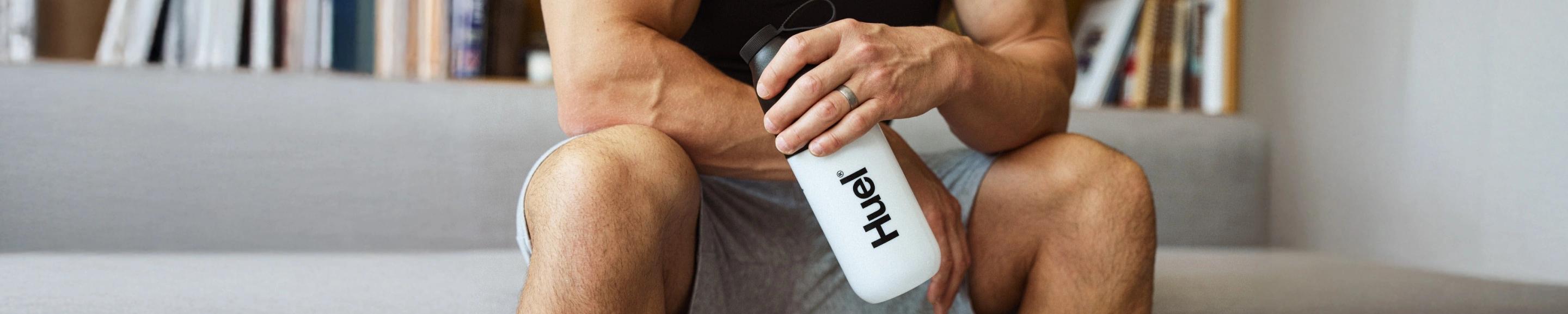 man sat on sofa holding a Huel shaker