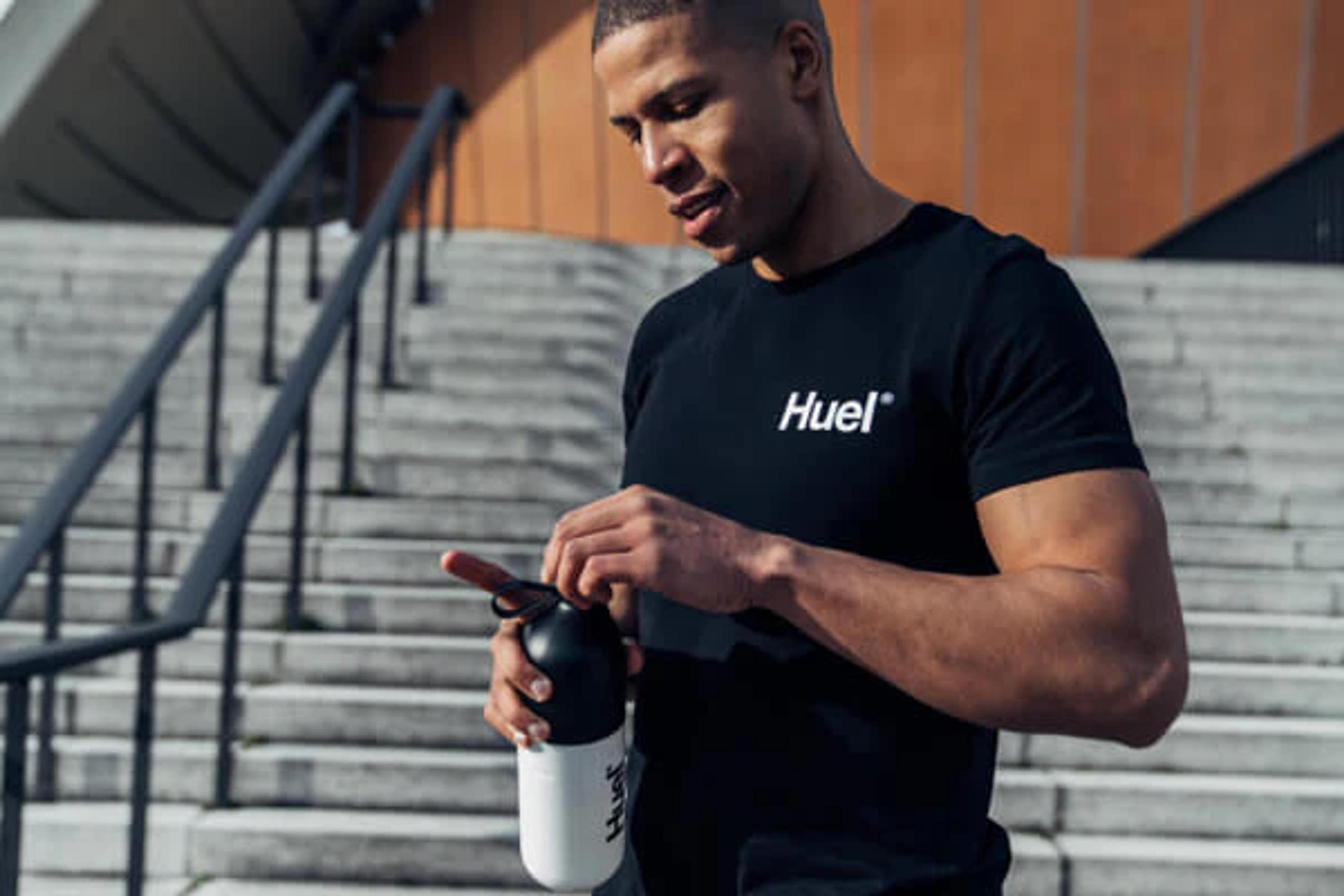 Man removing lid from Huel shaker whilst wearing a Huel t-shirt