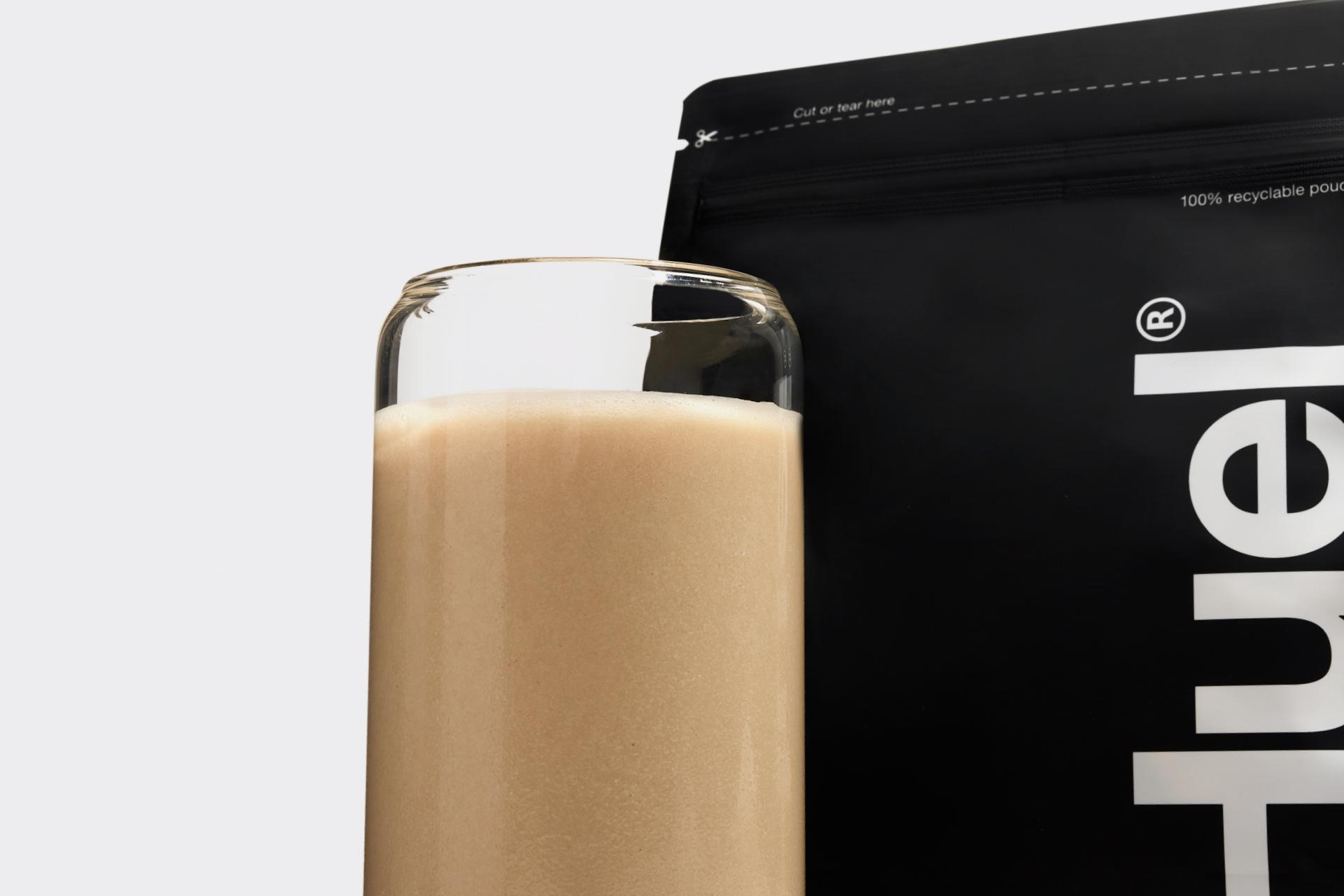 A glass of Complete Protein in front of the Complete Protein pouch