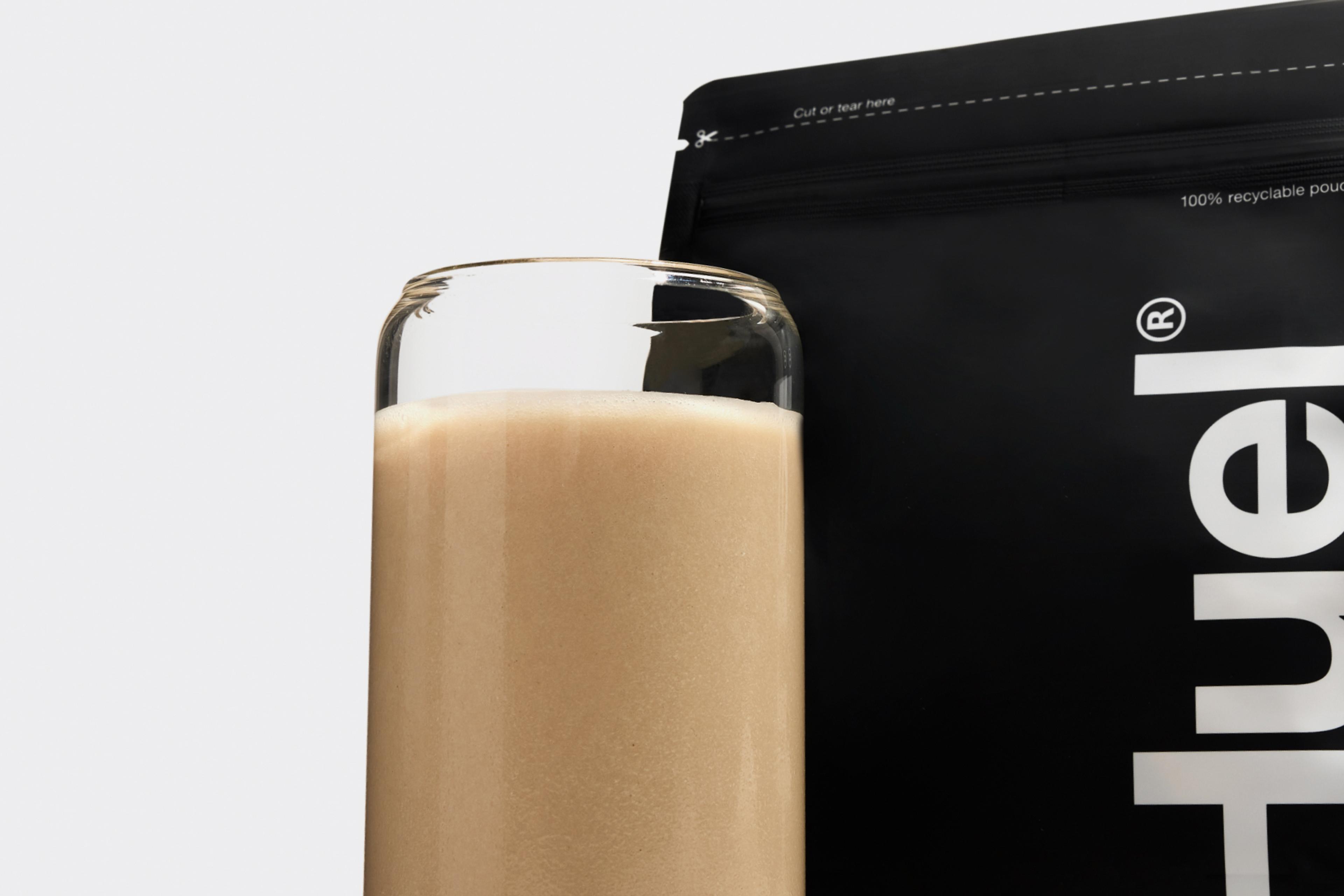 A glass of Complete Protein in front of the Complete Protein pouch
