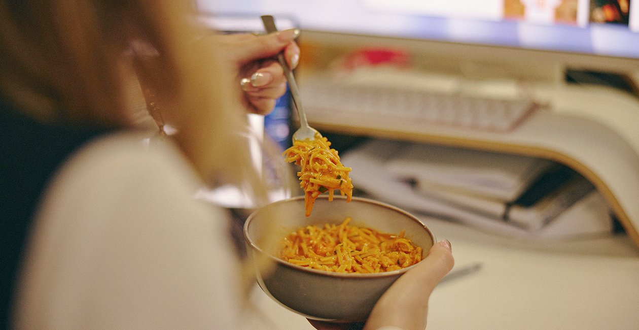 Person sat at their desk eating dinner late