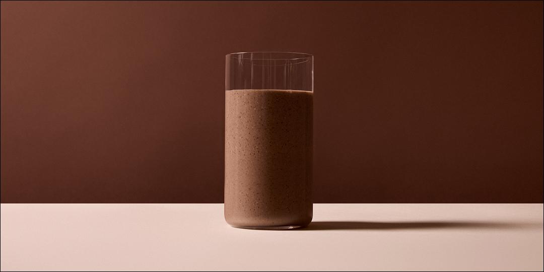 Close up image of a glass of Huel Black Edition on a brown background