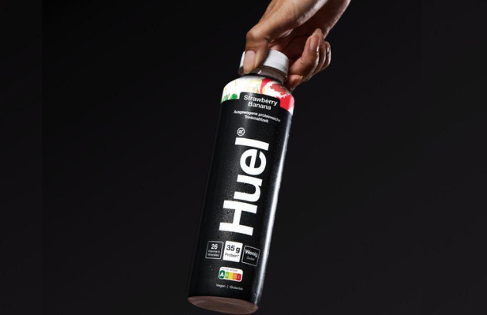 A bottle of Huel black edition ready-to-drink in strawberry and banana flavour on a black background
