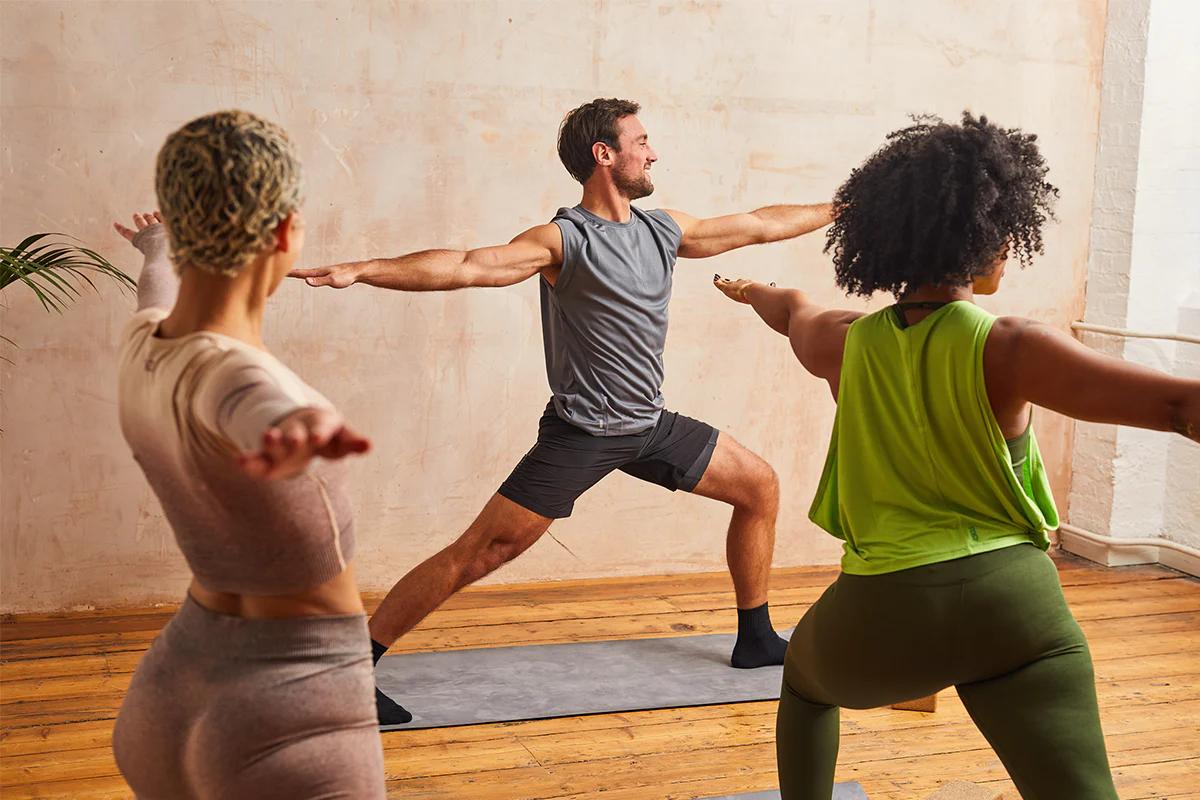 Three people doing yoga poses on yoga mats