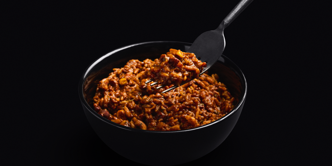 Close-up image of Huel Hot & Savoury Mexican Chilli on a black bowl, set against a black background