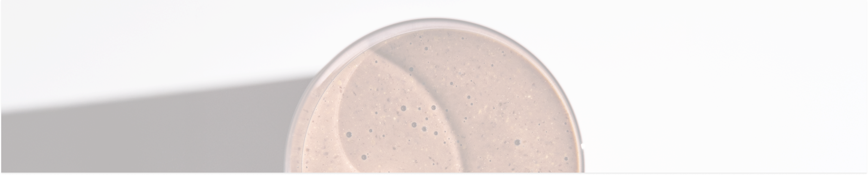 a close-up image of a glass of chocolate Huel shake set against a grey background