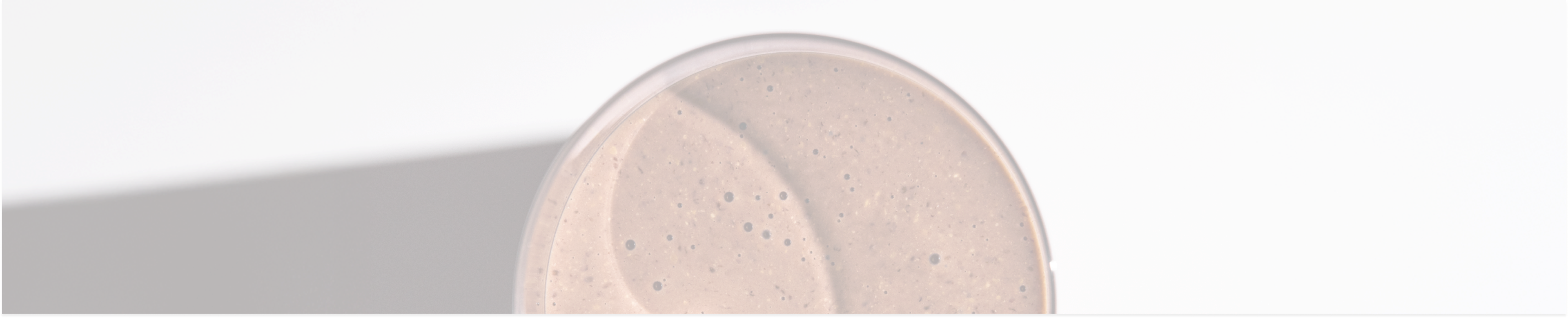 a close-up image of a glass of chocolate Huel shake set against a grey background