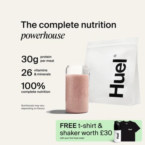A bag of Huel powder next to a glass containing a Huel drink on a neutral background