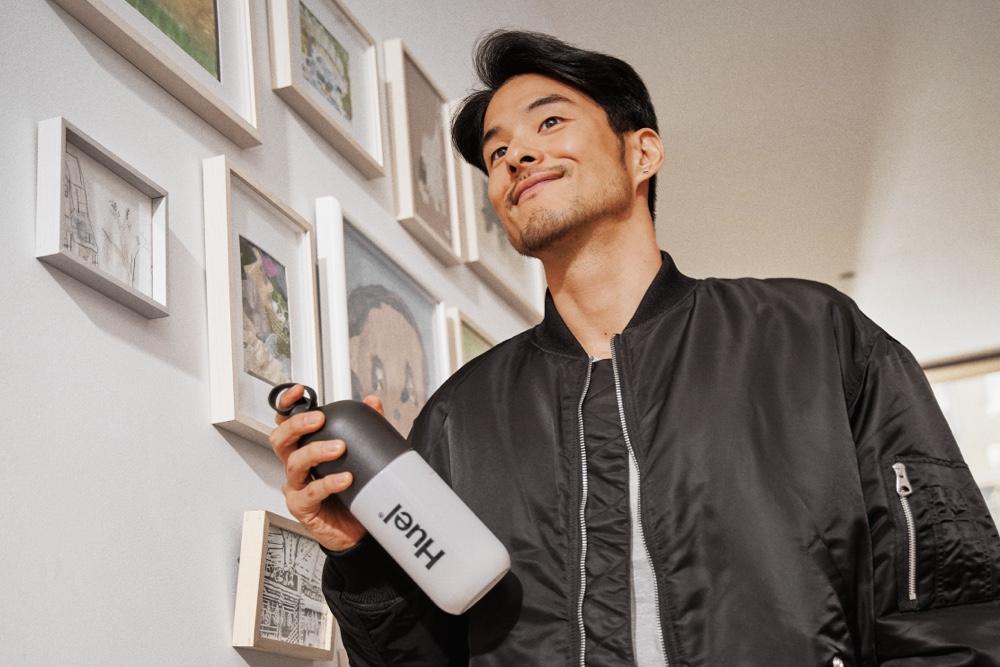 Man holding a Huel shaker walking through a house