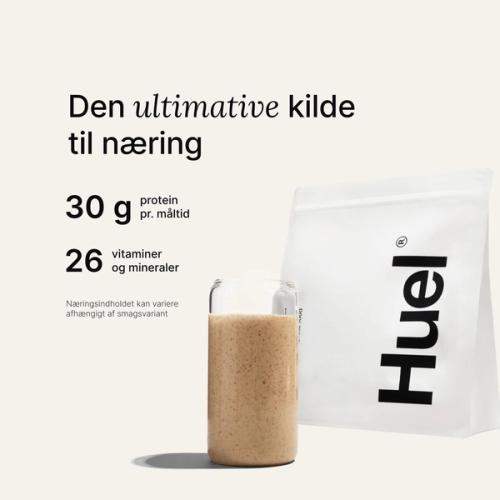 En pose med Huel-pulver ved siden af et glas med en drik fra Huel på neutral baggrund
