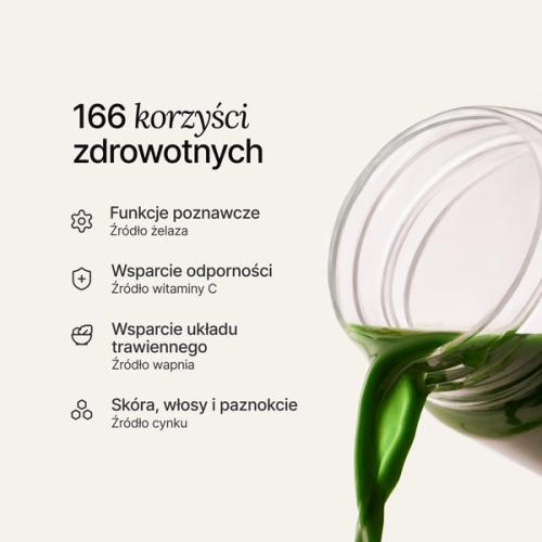 Ręka wsypująca miarkę Huel Daily Greens do przezroczystego shakera Daily Greens.