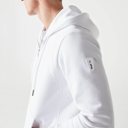 A man wearing a white huel hoodie with his hands in his pockets