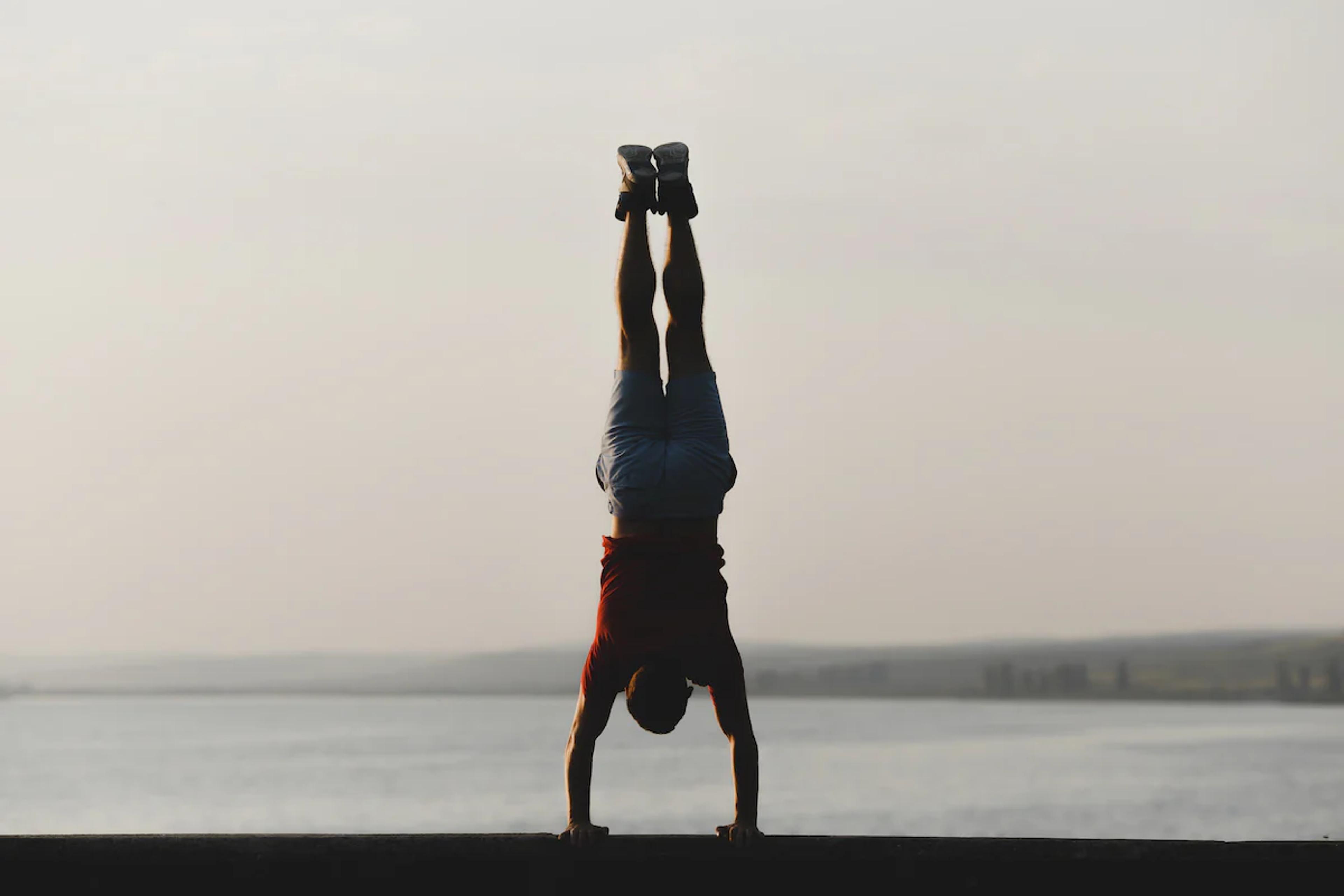 Man doing a handstand in front of the sea