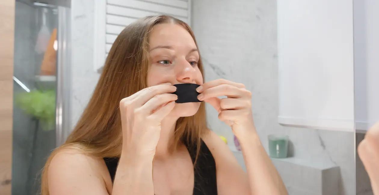 woman stood in bathroom putting tape over her mouth