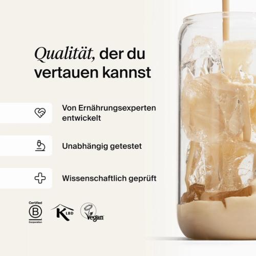 Huel vanilla shake being poured into a glass with ice, against a neutral background