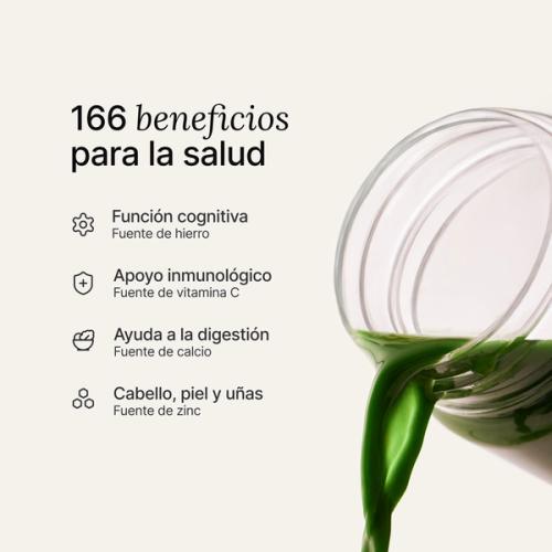 Mano vertiendo una medida de polvo Huel Daily Greens en un shaker de Daily Greens transparente.