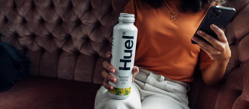 Woman on her phone holding a Huel Ready-to-drink