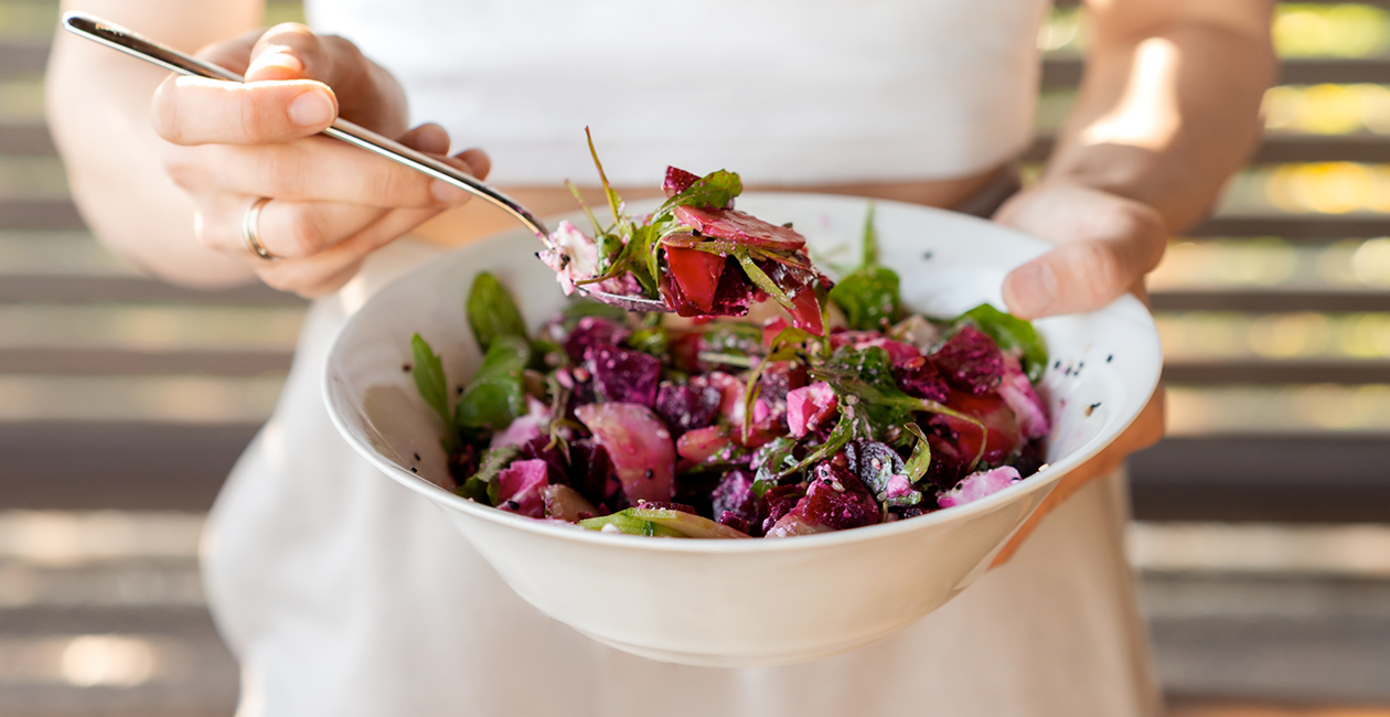 woman holding a bowl with a vibrant pink and green salad