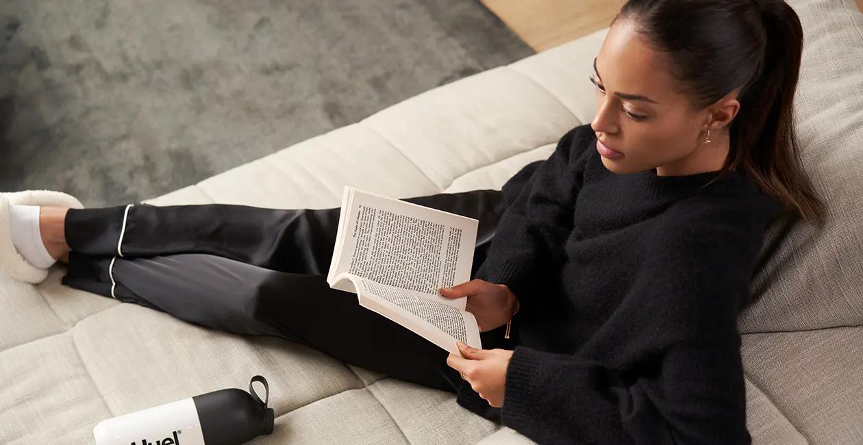 person sat on a sofa reading a book with their feet up