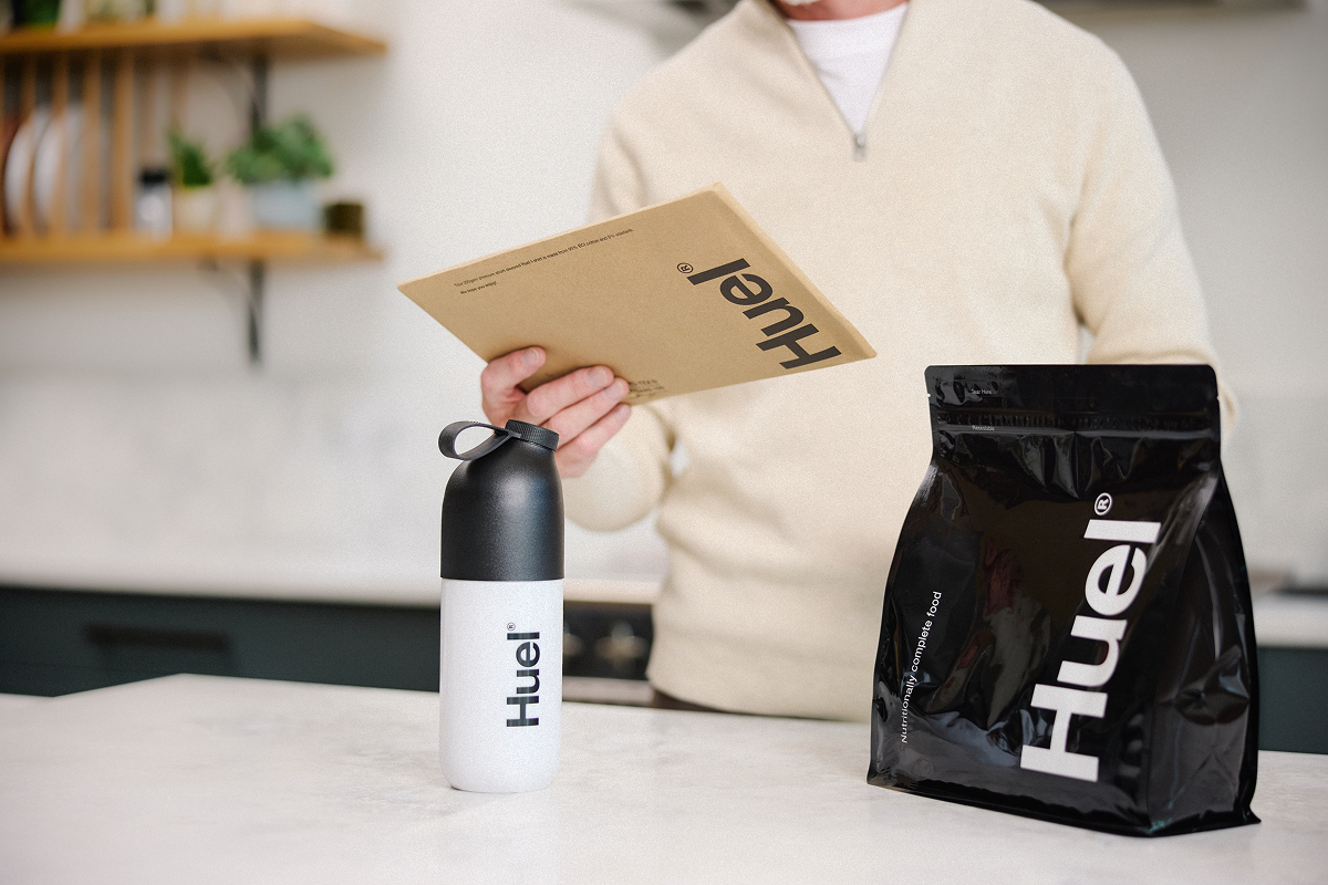 Man holding package with a shaker and Huel Black edition on the counter