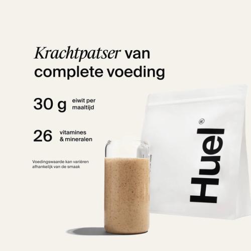 Een zak Huel-poeder naast een glas met een Huel-drankje op een neutrale achtergrond