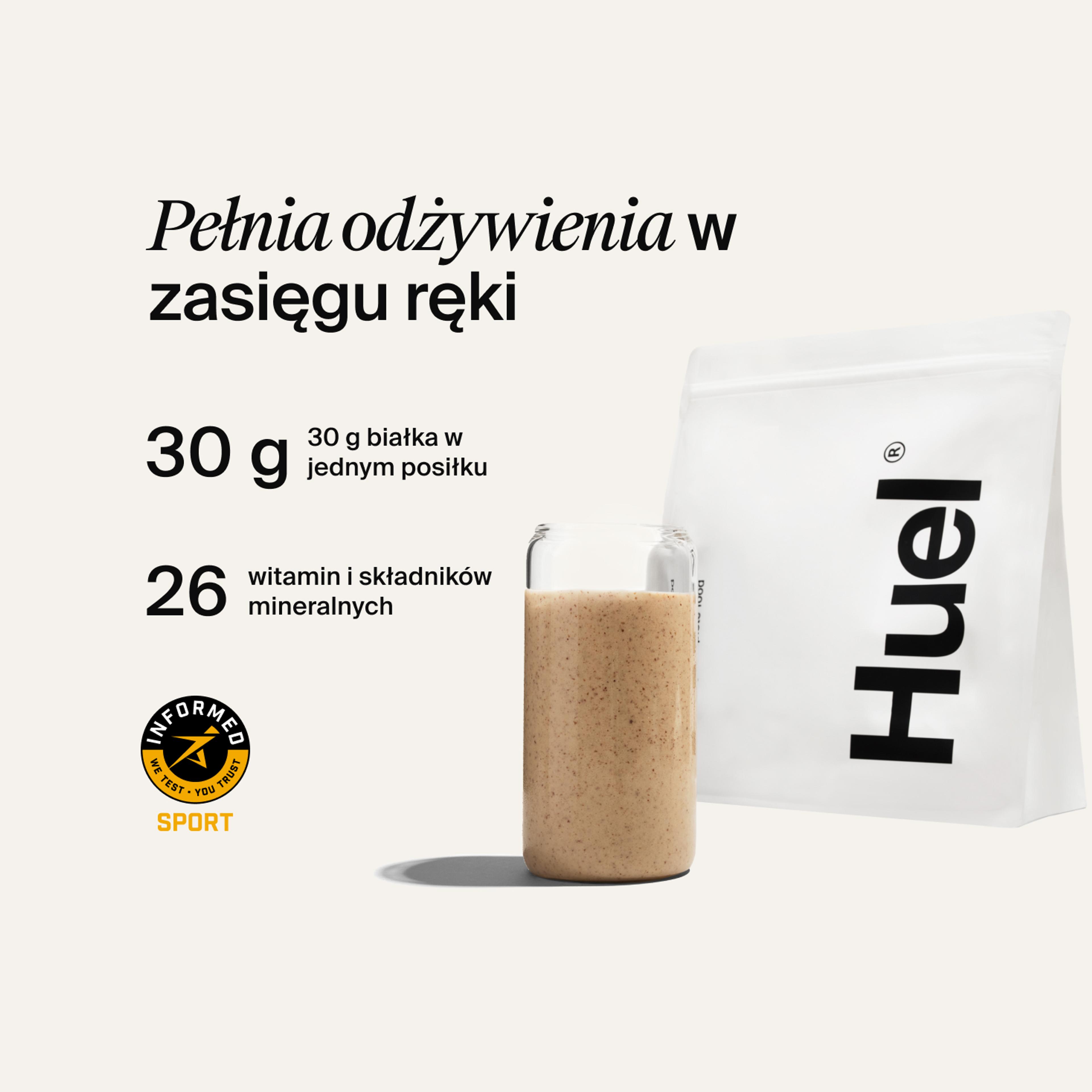 A bag of Huel powder next to a glass containing a Huel drink on a neutral background