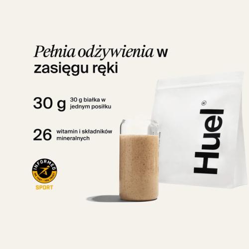 A bag of Huel powder next to a glass containing a Huel drink on a neutral background
