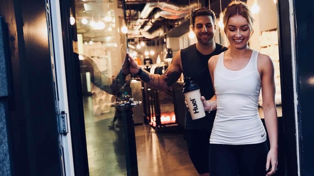Man and woman leaving gym with Huel shaker