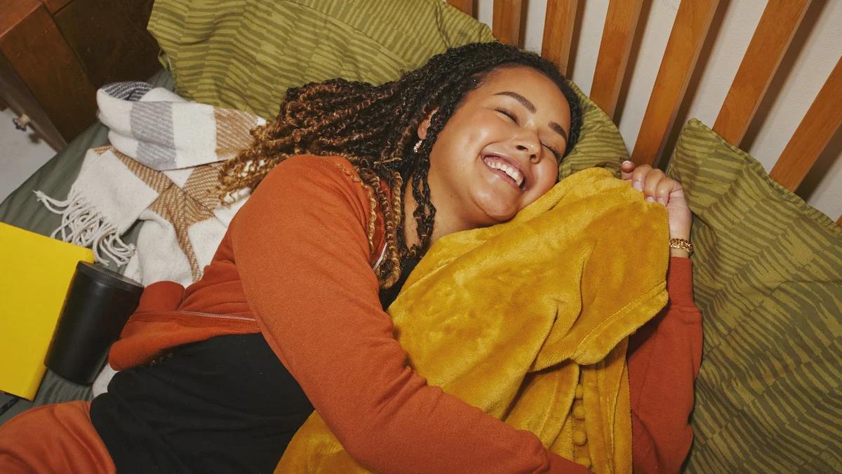 Woman Sleeping in bed hugging an orange blanket