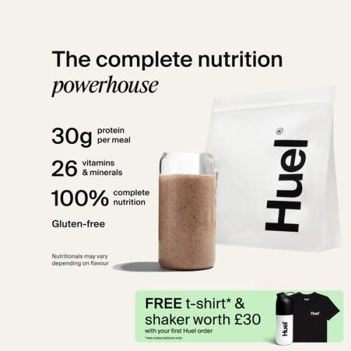 A bag of Huel powder next to a glass containing a Huel drink on a neutral background