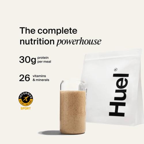 A bag of Huel professional powder next to a glass containing a Huel drink on a neutral background
