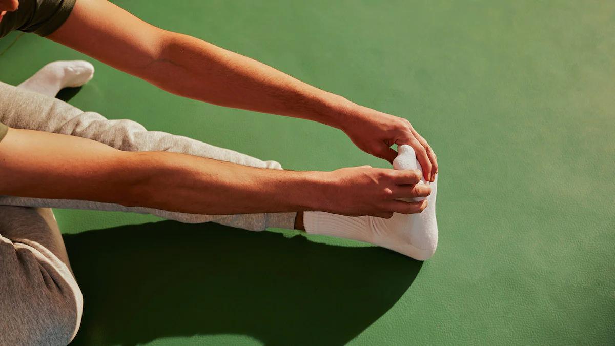 Someone stretching their leg and touching their toes whilst sat on the ground