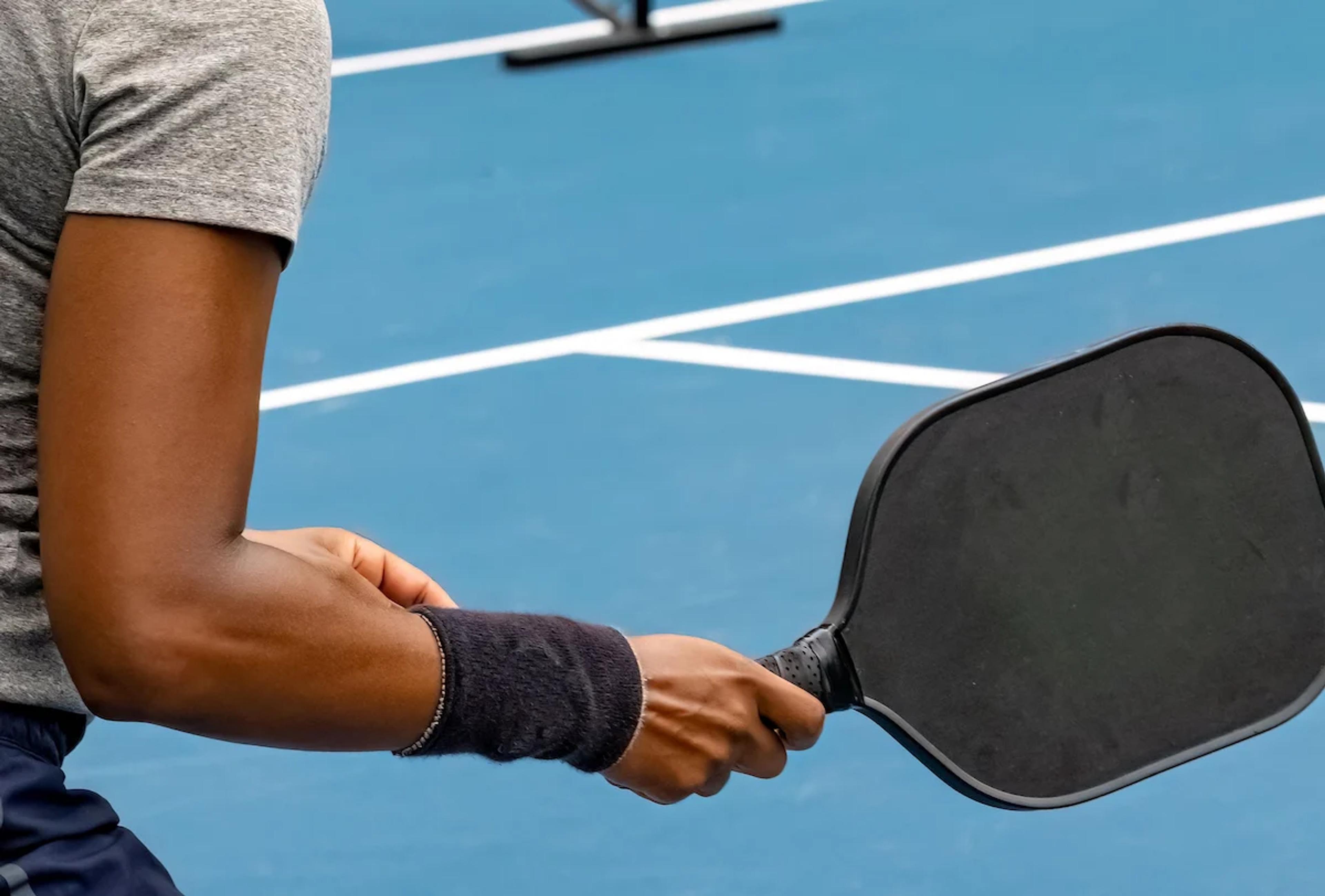 person on a pickleball court holding a pickleball racket