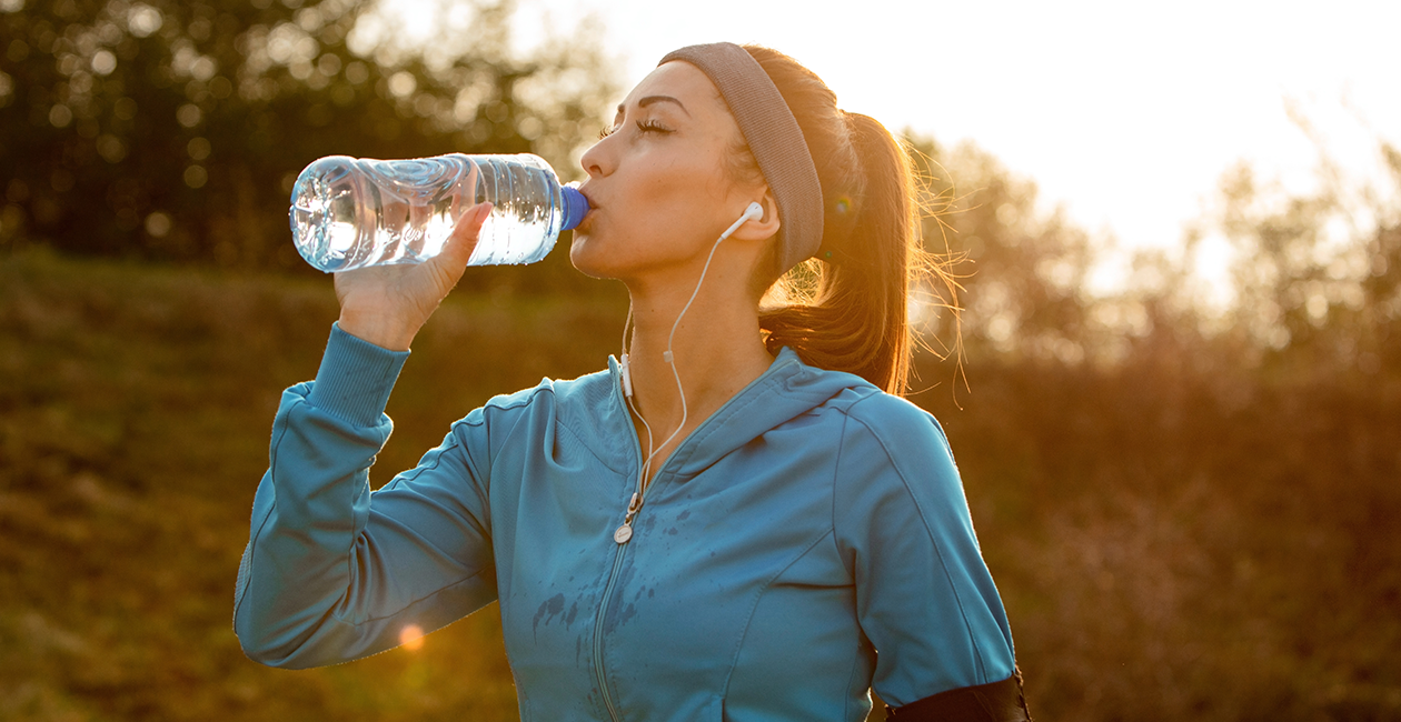 A woman in sports wear drinking from a bottle of water