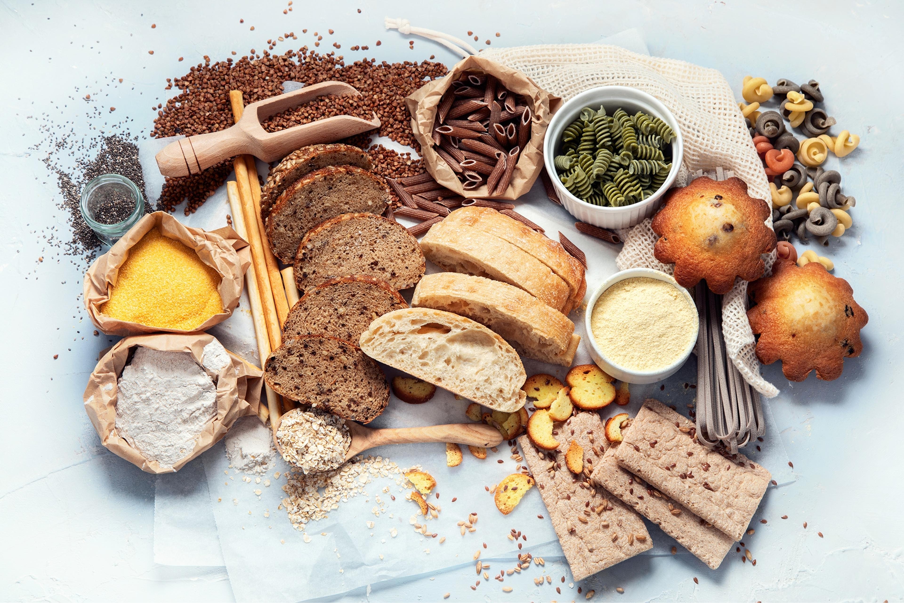 Different types of high carbohydrate food. Selection of good sources of carbs on grey background. Top view, flat lay.