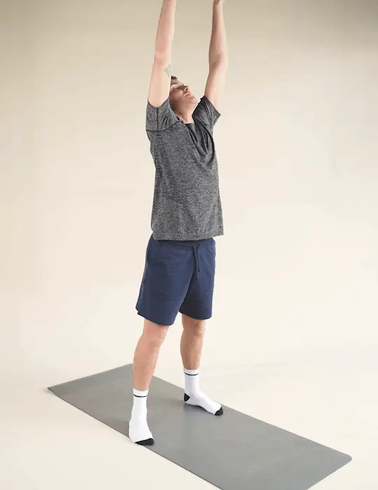 Man performing a Victory Pose stretch whilst stood on a yoga mat