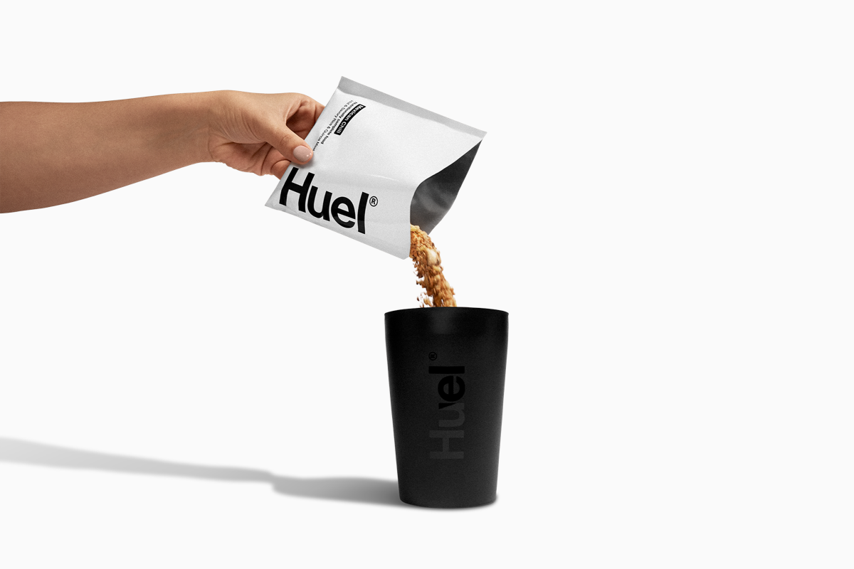 Image of someone pouring a sachet of Huel Hot & Savoury into a black Huel pot