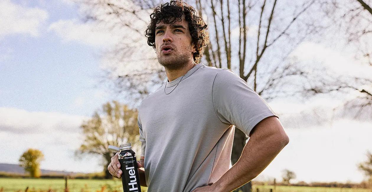 man outside catching his breath as he drinks a Huel Black Edition