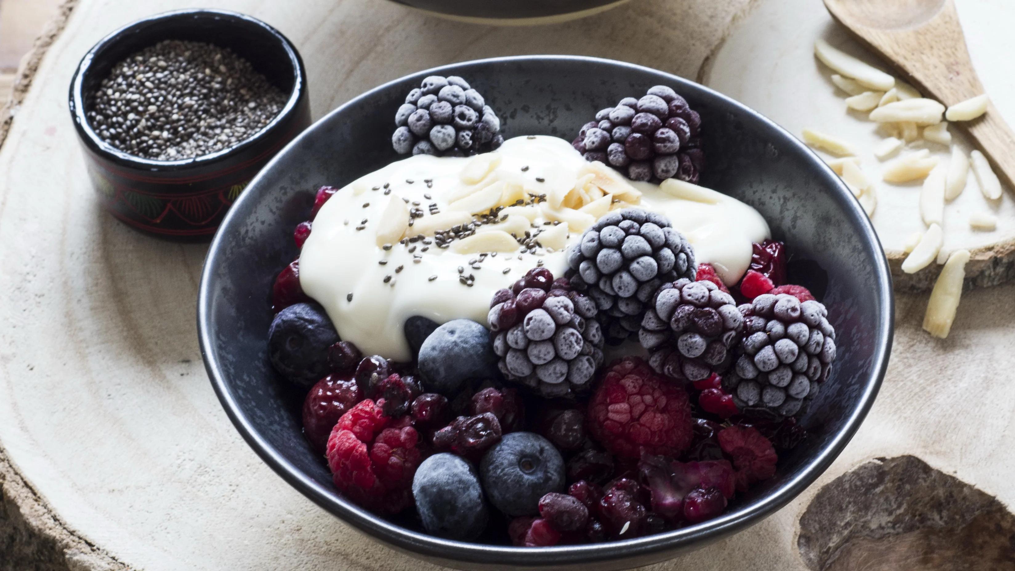 A bowl with blackberries, blueberries, raspberries, and redberries, with yoghurt and chia seeds on top