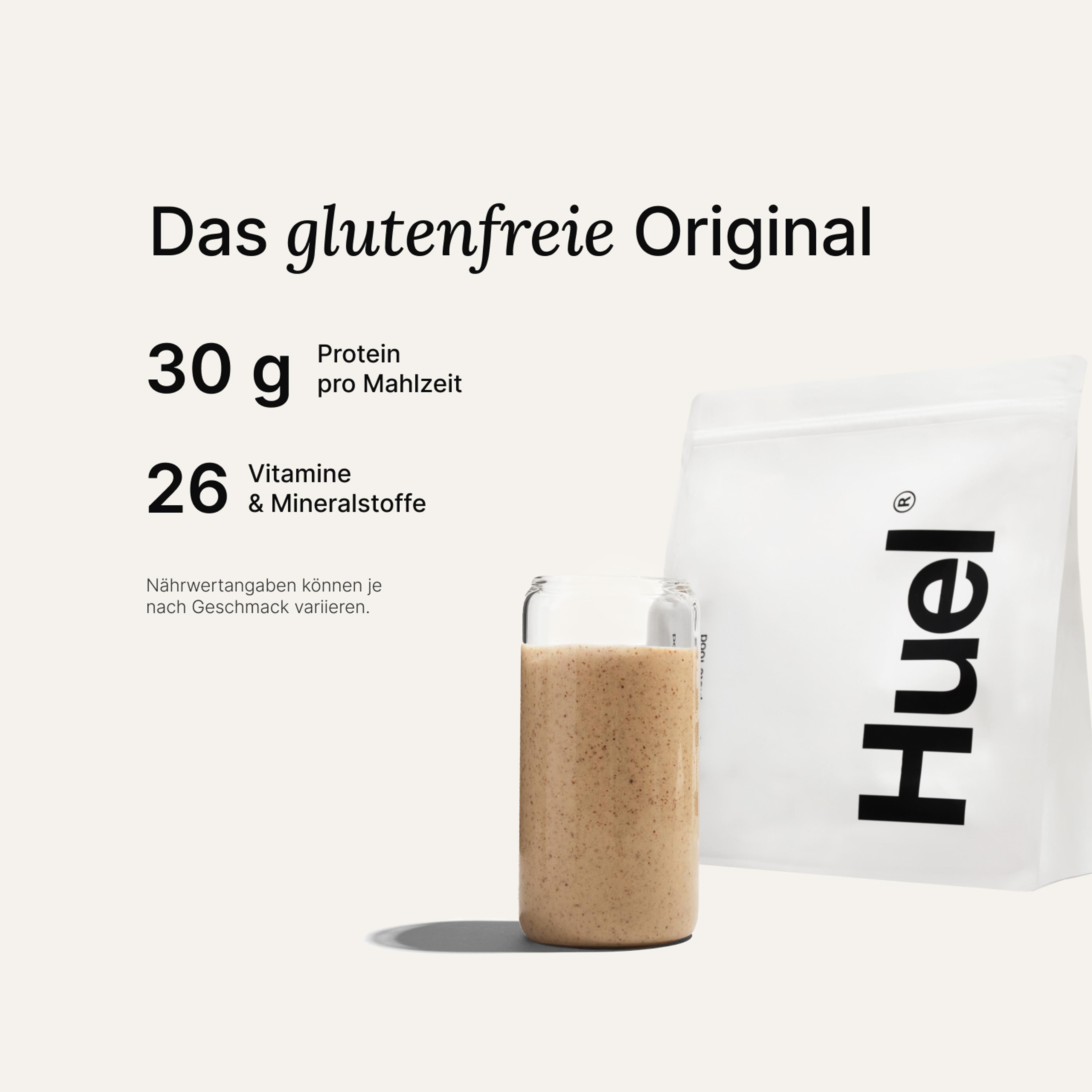 Ein Beutel Huel Pulver neben einem Glas mit einem Huel Drink vor einem neutralem Hintergrund
