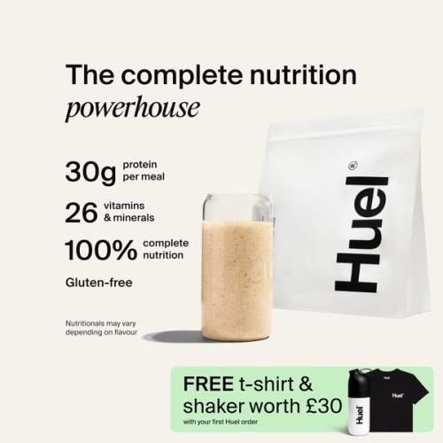 A bag of Huel powder next to a glass containing a Huel drink on a neutral background