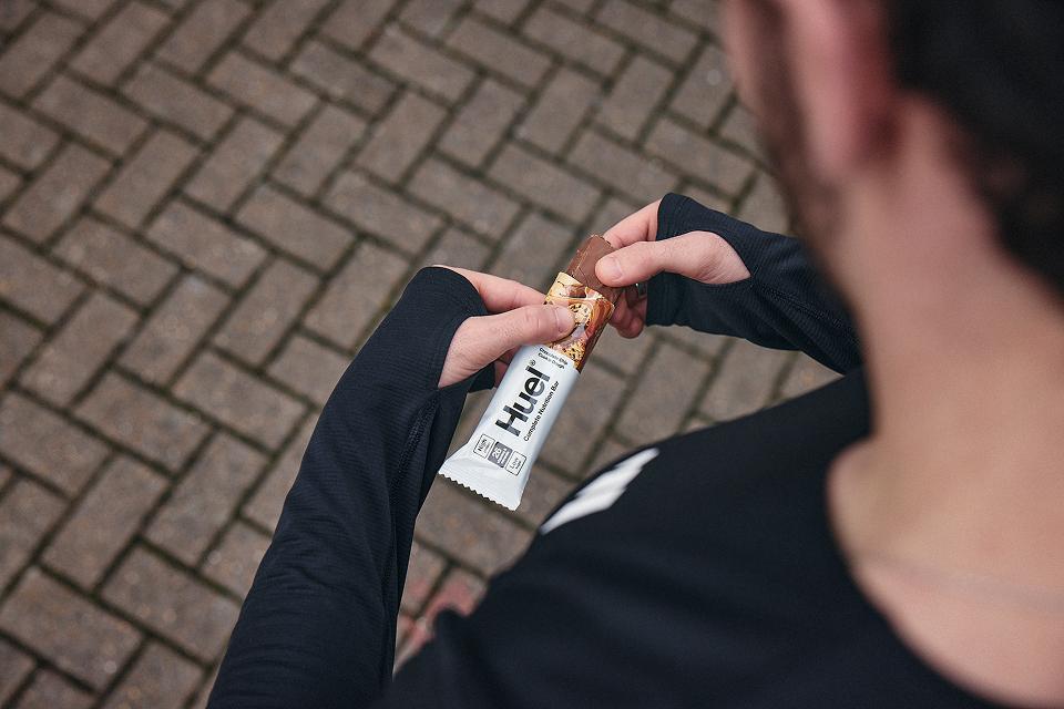 A man holding complete nutrition bar wearing a black sports top