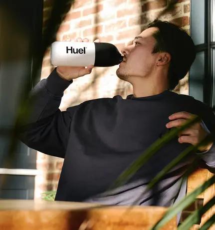 man drinking a vanilla Huel black edition ready-to-drink