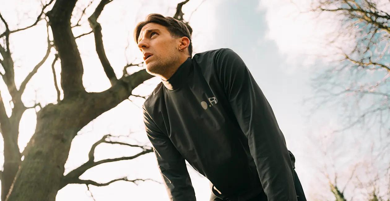 man bent over with his hands on his knees while outside catching his breath