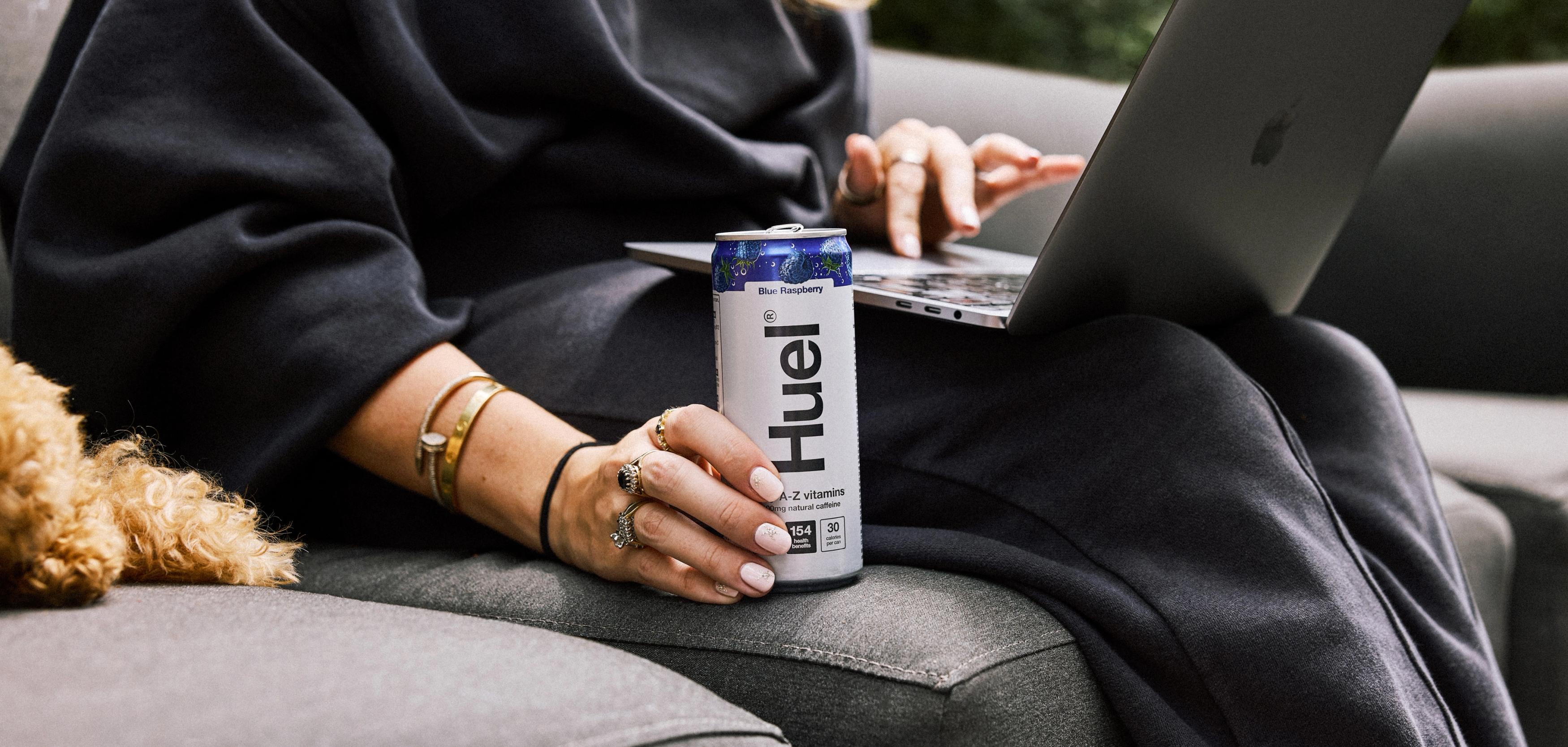Woman drinking from a white and pink Huel Daily A-Z Vitamins energy drink can