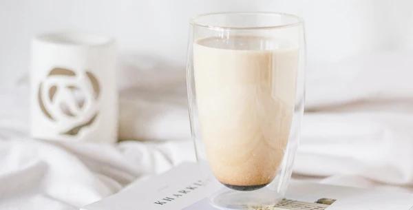 Glass of potato milk on a book on a bed