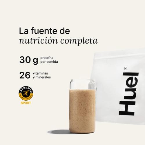 Una bolsa de Huel Powder junto a un vaso que contiene una bebida de Huel sobre un fondo neutro