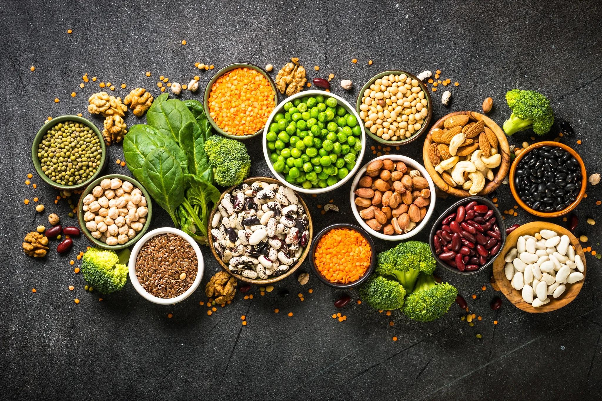 Top view of different vegan protein sources in bowls - including peas nuts grains and more