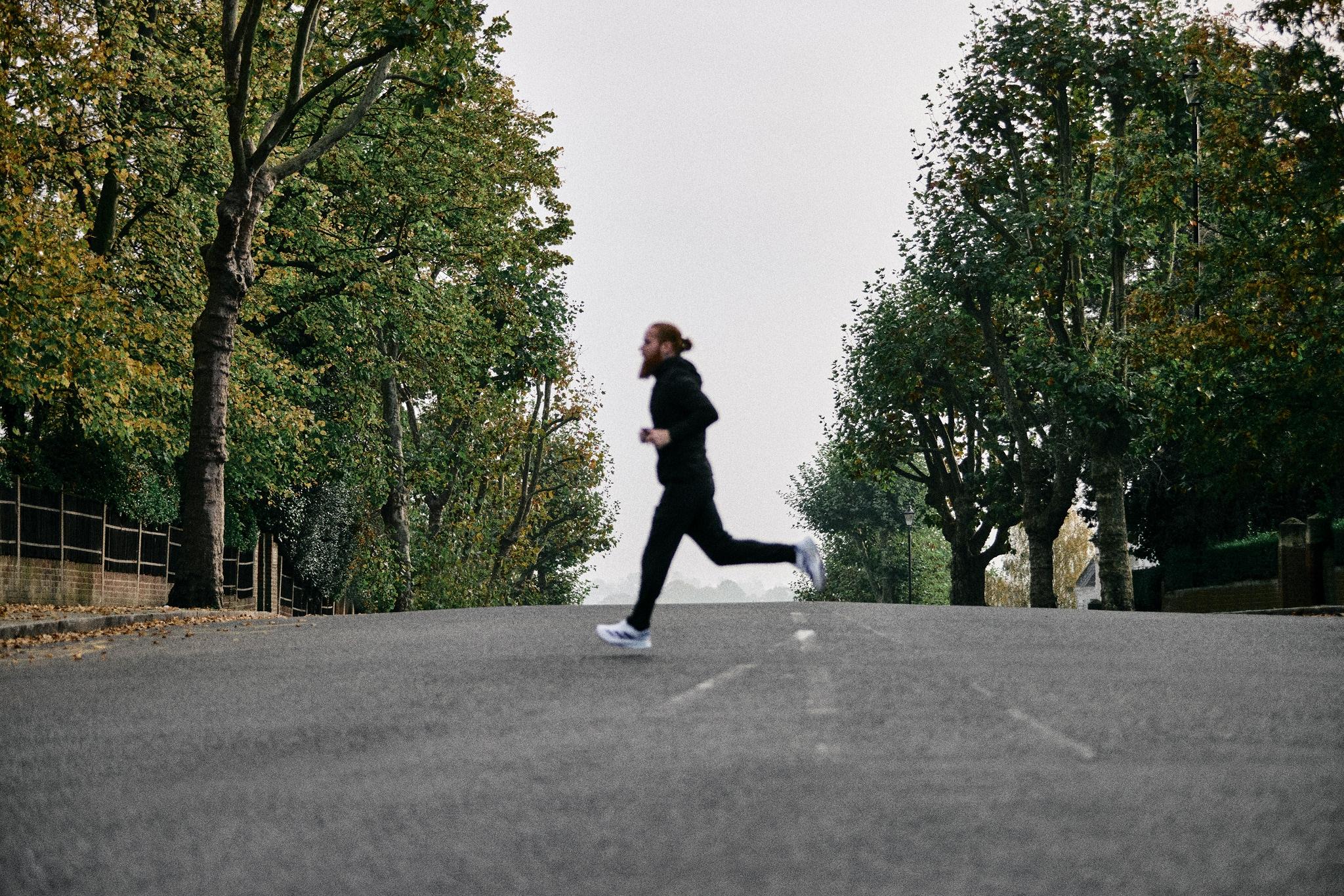 russ cook running across a road with trees either side