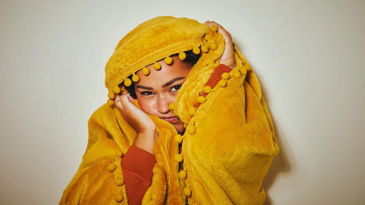 woman with a yellow blanket on her head pulling a face